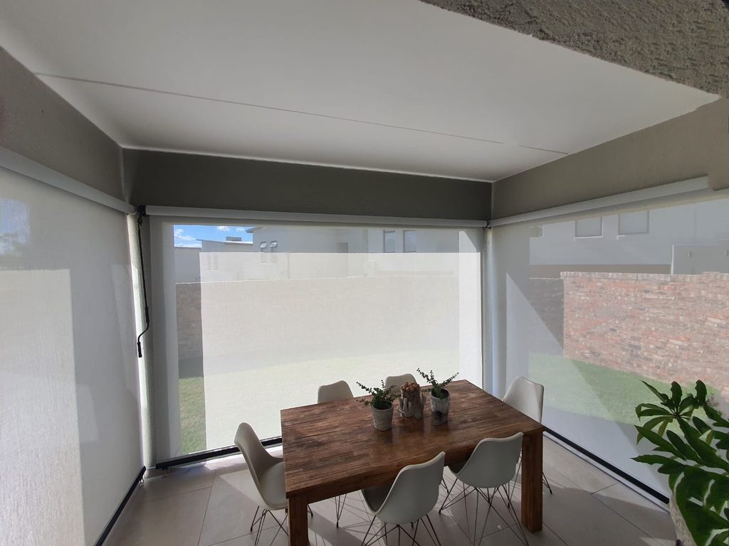 White sheer weave out door roller blinds installed on a covered outdoor patio - Inside view